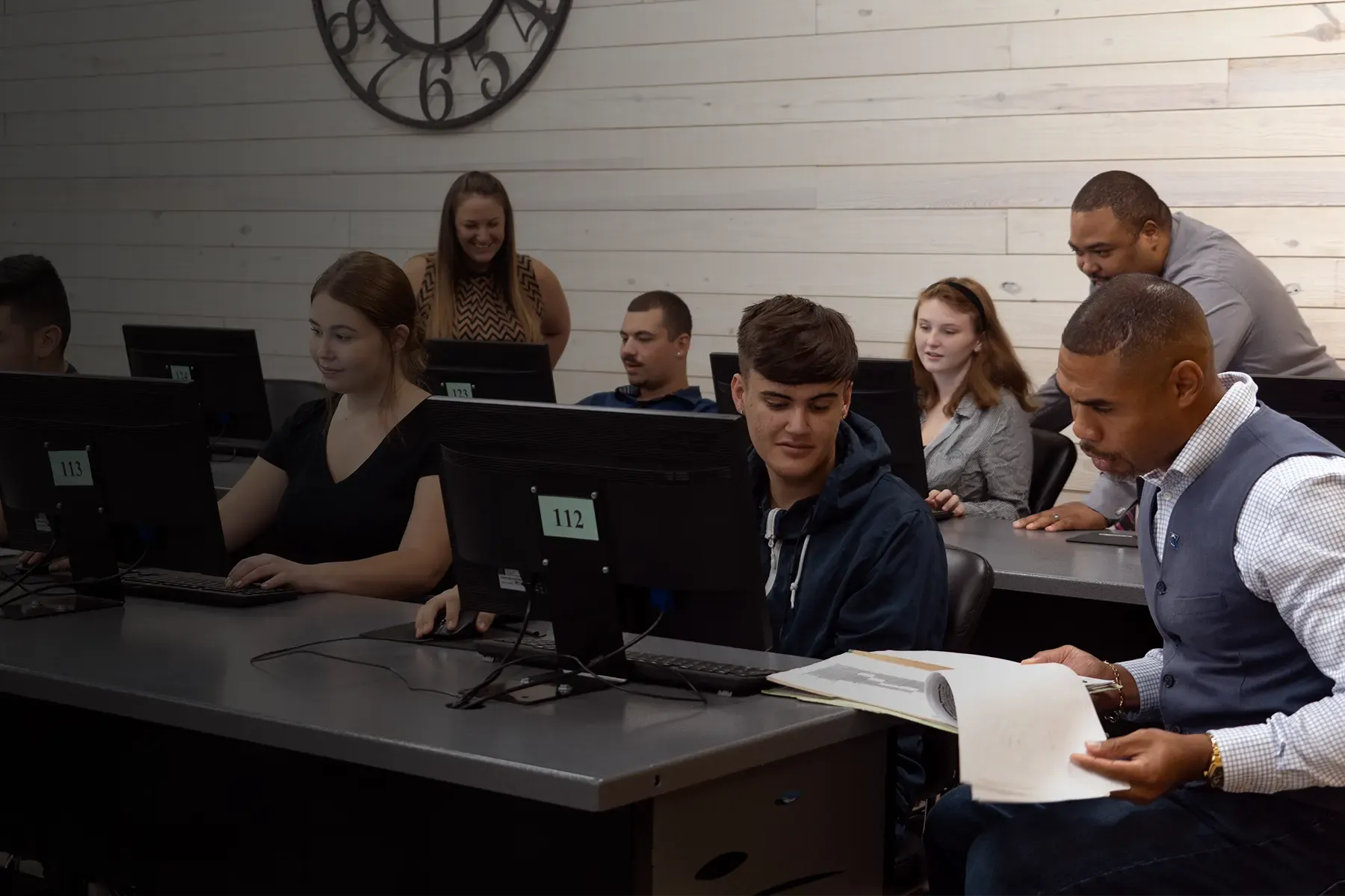 Students using a computer lab with the help of teaching staff.